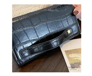 Detail of black crocodile texture leather wallet with gold snap button and wrist strap