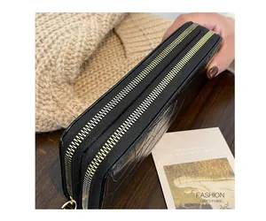 Detail of black crocodile embossed long wallet with dual gold zippers on a wooden surface