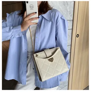 Détail d'un sac en cuir matelassé beige avec fermoir cœur doré et bandoulière chaîne