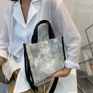 Detailed shot of grey marble print canvas tote bag styled with casual white shirt and khaki pants