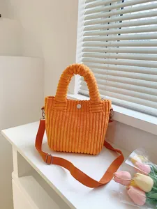 Detail of bright orange corduroy bucket bag with wide top handle and matching nylon strap