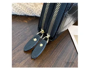 Detailed macro shot of dual gold zippers and crocodile texture on a black lady's purse