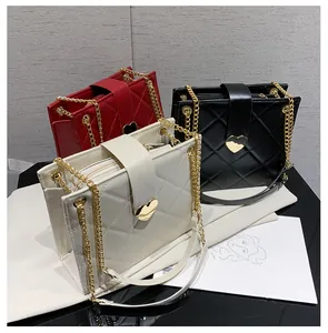 Détail de sacs bandoulière matelassés en blanc, rouge et noir avec fermoirs en cœur doré