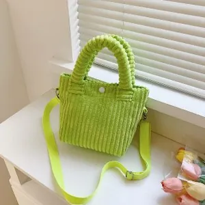Detail view of lime green corduroy handbag with textured fabric and white snap closure