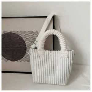 Close-up of white corduroy bucket bag texture with top handle and woven shoulder strap