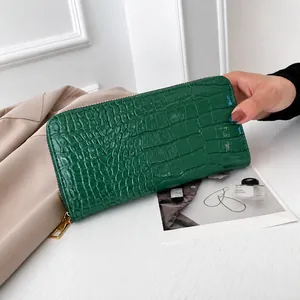 Primer plano de cartera larga verde con textura de cocodrilo y cremallera dorada