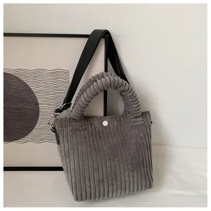 Close-up of dark grey corduroy bucket bag texture with white snap button and strap