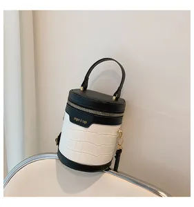 Detail einer zylindrischen Eimertasche in Schwarz-Weiß mit markanter Krokodil-Prägung