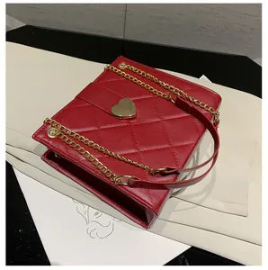 Détail du sac bandoulière en cuir matelassé rouge avec fermoir doré en forme de cœur