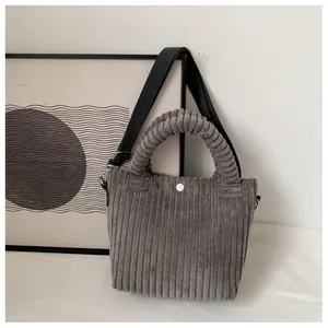 Detail of dark grey corduroy texture and pleated handle on minimalist bucket bag