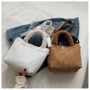 Detail view of corduroy bucket bags in white and brown colors on blue denim fabric