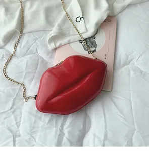 Detail of red lip-shaped crossbody bag with glossy patent finish and gold chain