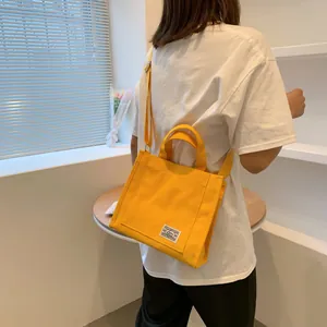Detail of yellow canvas tote bag featuring retro fabric label and adjustable strap