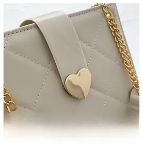 Détail du sac en cuir matelassé beige avec fermoir cœur doré et bandoulière