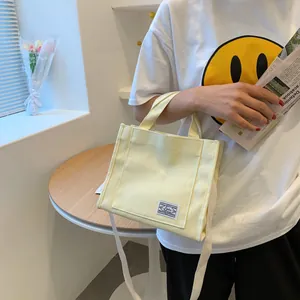 Detail of light yellow canvas tote bag with shoulder strap and stylish woven label