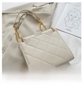Détails de la texture en cuir matelassé beige et de la chaîne dorée du sac à bandoulière