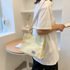 Detail of a thick beige canvas tote bag showing the side view and adjustable strap