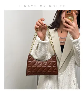 Detail of a brown quilted underarm bag featuring a chunky gold chain and metal zipper
