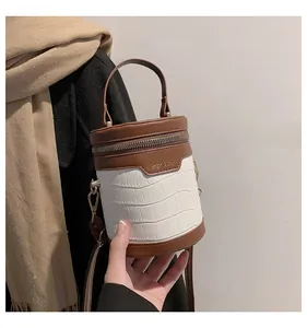 Detail der Retro-Zylindertasche mit weißer Krokodil-Prägung im Farbblock-Design