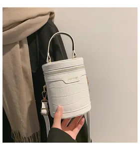 Detail einer weißen Zylindertasche mit Krokodilmuster, Rundgriff und Goldbeschlägen