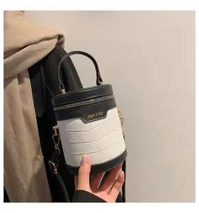 Details der schwarz-weißen Zylindertasche mit Krokostruktur und goldenem Reißverschluss