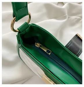 Détail d'un sac à bandoulière en cuir vert foncé avec fermeture éclair et métal doré