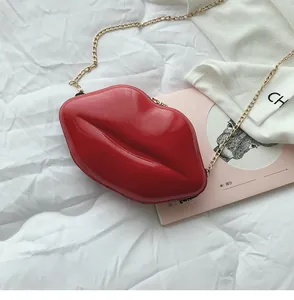 Glossy red lip-shaped hard shell mini bag with gold chain strap on soft white fabric