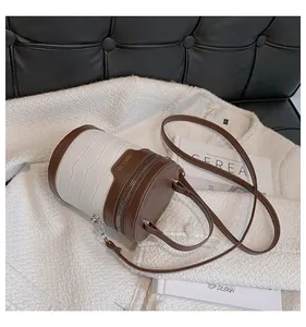 Detail der vintage zylindrischen Tasche mit weißer Krokoprägung und braunem Lederbesatz