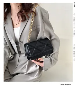 Close-up of a black quilted flap crossbody bag with a chunky gold chain strap on a model