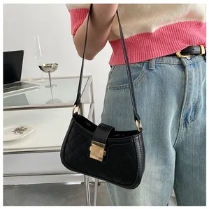 Détail du sac d'épaule matelassé noir avec boucles dorées dans un décor moderne chic
