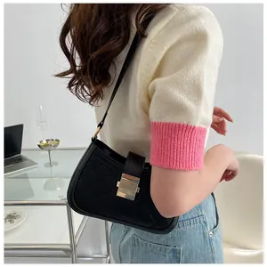 Détail d'un sac à bandoulière noir matelassé avec boucle dorée porté par un mannequin