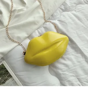 Macro shot of stylish bright yellow lip-shaped chain bag with glossy finish and gold strap