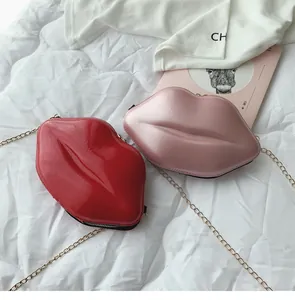 Macro view of lip-shaped crossbody bags in glossy red and matte pink with gold chain