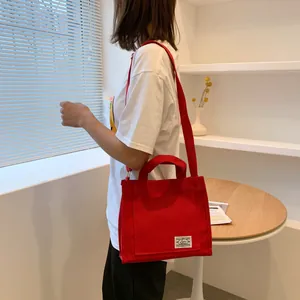 Detail of red canvas handbag with woven label and adjustable shoulder strap for women