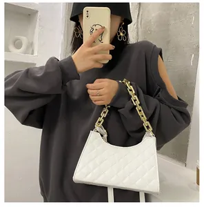 Détail d'un sac bandoulière matelassé blanc avec chaîne dorée épaisse porté par un mannequin