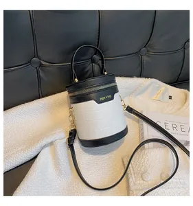 Detailaufnahme der schwarz-weißen Zylindertasche mit Krokodilmuster und goldener Hardware