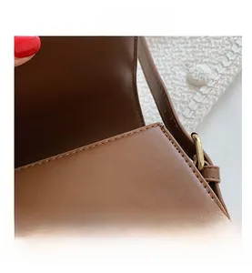 Detail of a brown leather saddle bag featuring a golden round magnetic snap closure
