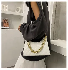 Détail d'un sac bandoulière blanc matelassé avec une grosse chaîne dorée et finitions