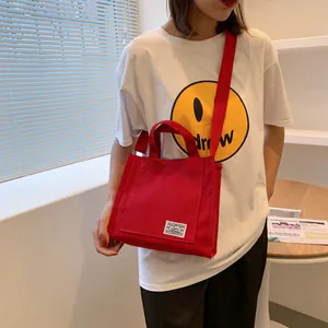 Detail of red canvas tote bag with shoulder strap and minimalist label on front side