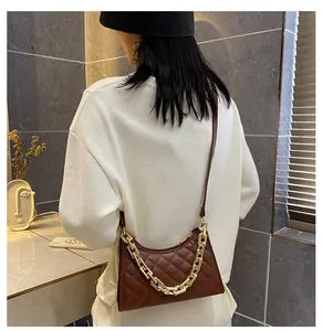 Détail du sac bandoulière marron matelassé avec chaîne dorée sur un mannequin femme