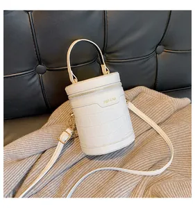 Details der weißen Zylinder-Tasche mit Kroko-Prägung, Gold-Hardware und Markenschrift