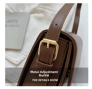 Macro shot of gold hardware adjustment buckle on dark brown leather shoulder bag strap