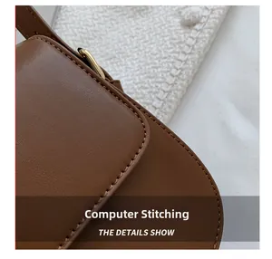 Detail shot of the computer stitching and gold hardware on a brown leather saddle bag