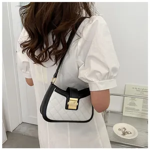 Détail du matelassage blanc en losanges avec garniture en cuir noir et métal doré