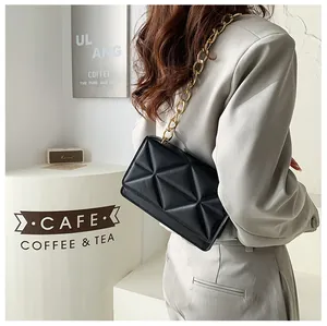 Detailed view of black crossbody bag with quilted triangle texture and gold chain strap