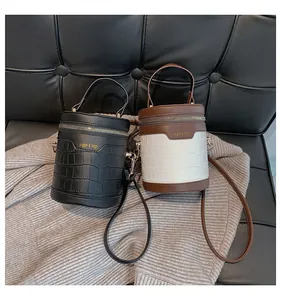 Details von Zylindertaschen in Schwarz und Braun mit strukturierter Krokodilhaut-Prägung
