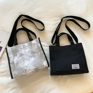 Minimalist canvas tote bags in grey marble and black, showing handles and shoulder straps