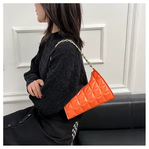 Vibrant orange quilted shoulder bag with gold chain strap shown on a model