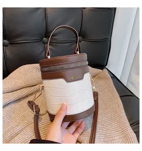 Detailansicht der weißen Zylindertasche mit Krokoprägung und braunem Ledergriff