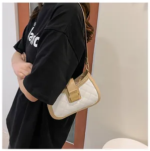 Détail du sac à main matelassé blanc avec fermoir doré et bordure beige porté à l'épaule